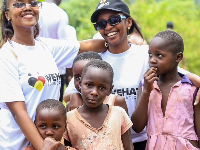 two ladies wearing white t-shirts with the wehat foundation logo standing with four girls from the community during a wehat foundation outreach